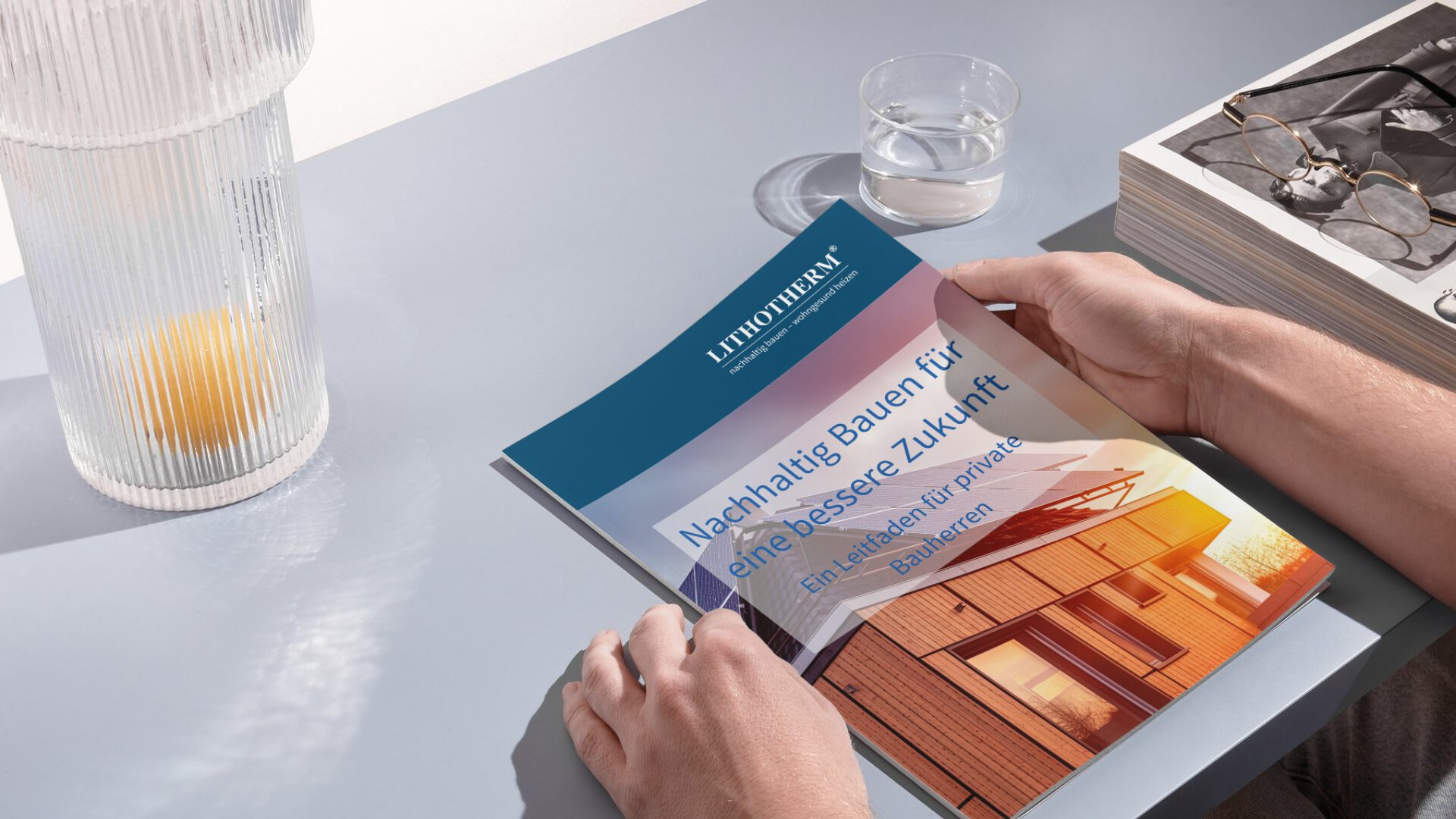 Das Cover des kostenlosen Leitfadens 'Nachhaltig bauen für eine bessere Zukunft' auf einem Tisch mit Planungsutensilien, symbolisiert umfassende Anleitung für Bauherren.