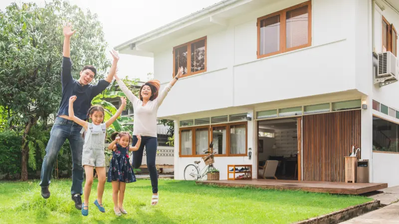 Glückliche Menschen vor einem modernen, nachhaltig gebautem Haus, die den Traum vom nachhaltigen Wohnen verwirklicht haben.